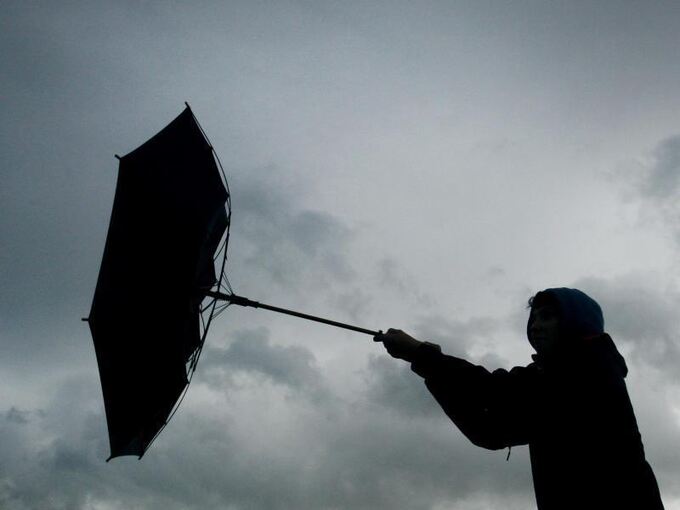 Windböe erfasst den Regenschirm eines Spaziergängers