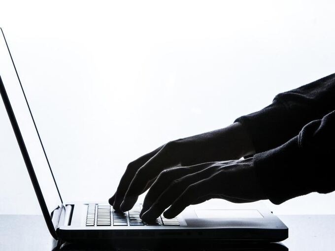 Ein Mann tippt auf einer Tastatur eines Laptops