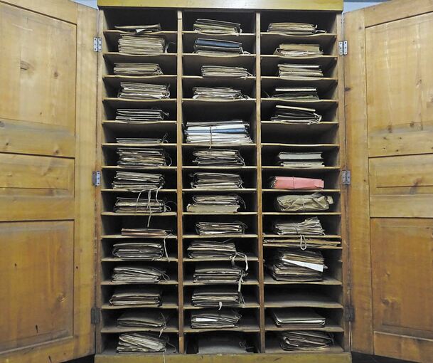 Der alte Holzschrank in seinem Originalzustand wie er bei der Renovierung vorgefunden wurde. Und ein Blick auf die handschriftlichen Akten.Fotos: Stadtarchiv