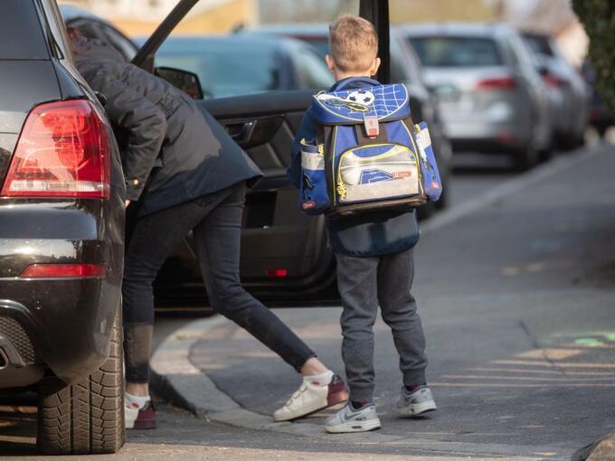 Ein Grundschüler steht neben einem Auto