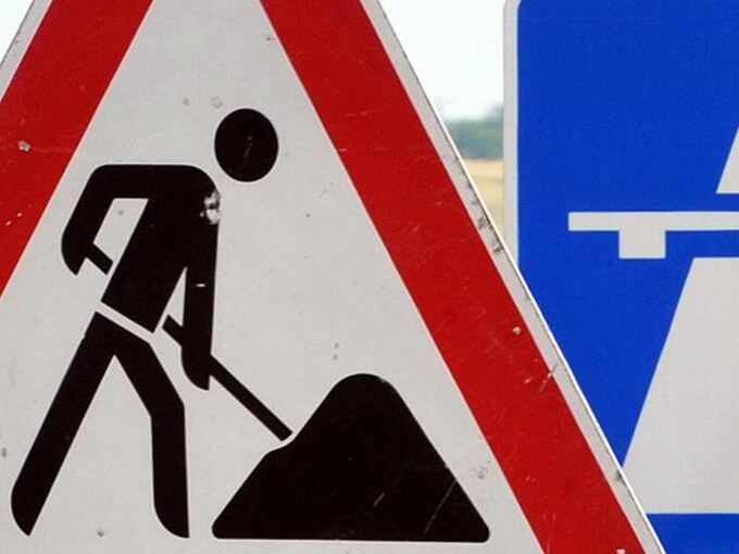 Ein Baustellenschild vor einem Autobahnschild