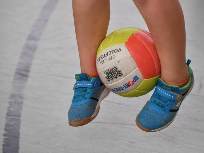Ein Kind hüpft mit einem Ball zwischen den Beinen