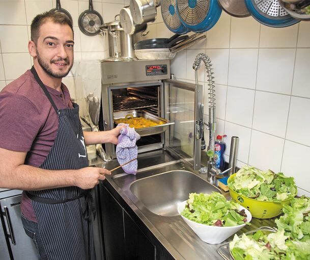 Koch Pavlos Papadopoulos bereitet die gebratenen Zucchinistreifen für den Salat vor.