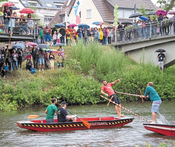 Viele Besucher kommen auf das Neckarremser Straßenfest – und stellen sich bei Regen dann eben einfach mit Schirm ans Ufer, um beim Fischerstechen zuzuschauen. Fotos: Andreas Essig