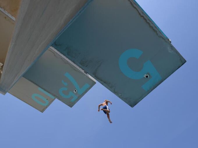 Ein Mann springt im Freibad vom 7,5--Meter-Turm
