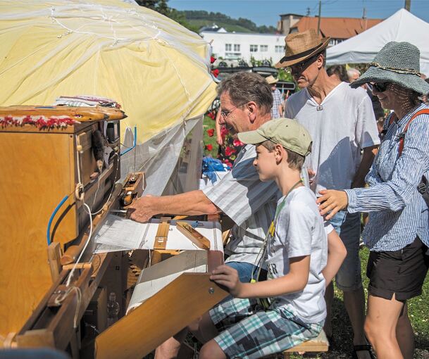 Interessierte blicken dem Weber neugierig über die Schulter.