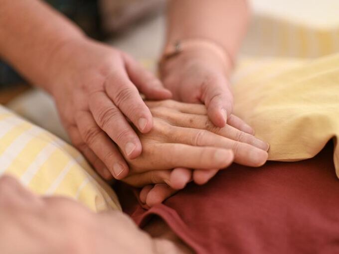 Eine Pflegerin hält die Hand eines Patienten
