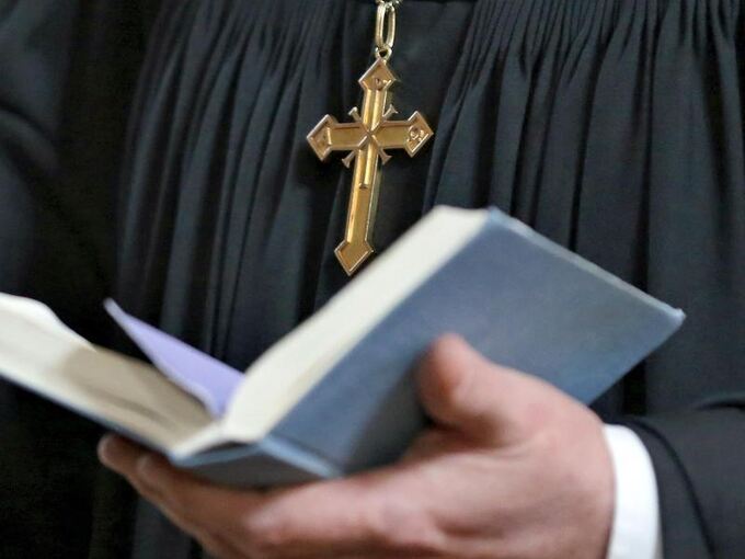 Eine Pfarr-Person hält eine Bibel in den Händen
