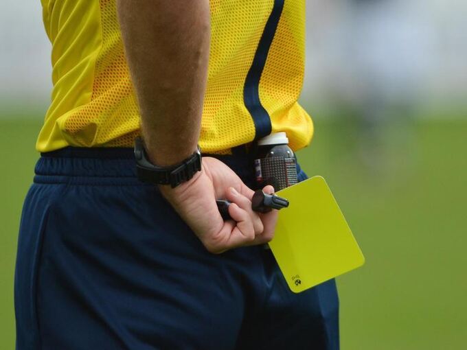 Ein Schiedsrichter hält die Gelbe Karte bereit