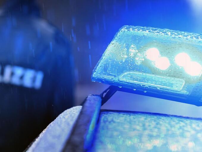 Ein Polizist steht im Regen neben Blaulicht
