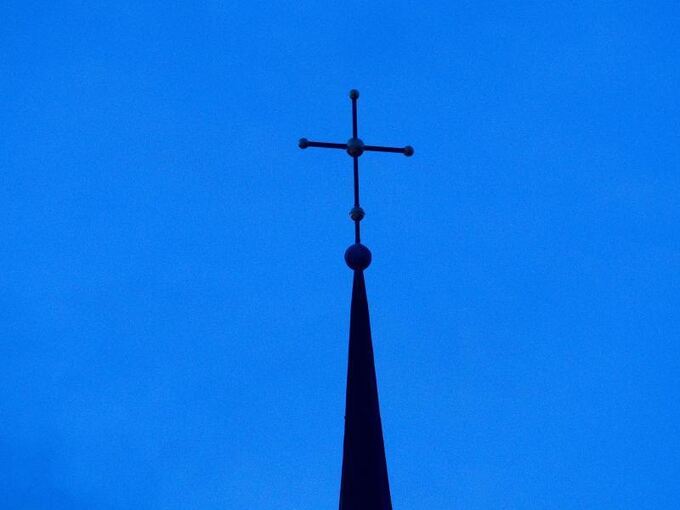 Ein Kreuz sitzt auf einer Kirchturmspitze