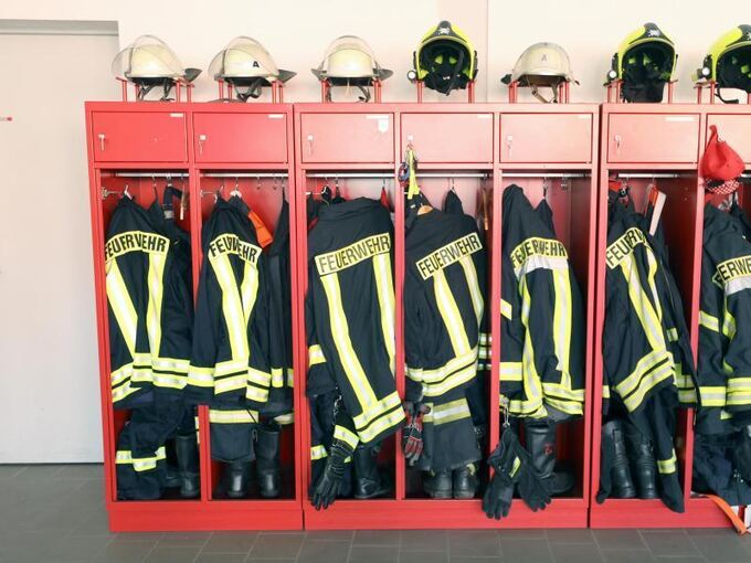 Uniformen der Feuerwehr hängen in einem Schrank