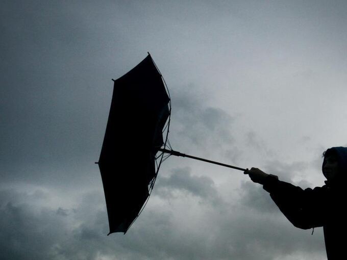 Ein Regenschirm einer Fußgängerin wird von einer Winböe erfasst