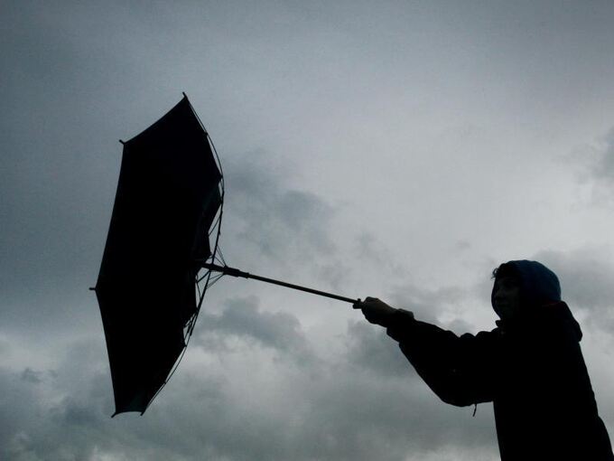 Eine Windböe erfasst den Regenschirm eines Spaziergängers