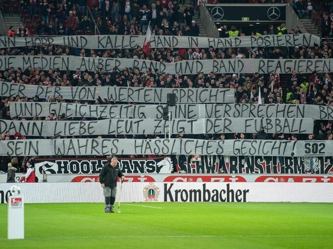 Fans des VfB Stuttgart halten ein Banner nach oben