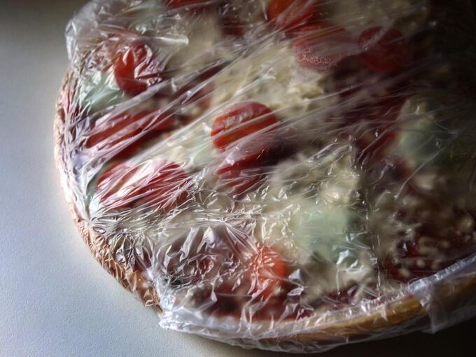 Eine in Plastikfolie gepackte Tiefkühlpizza