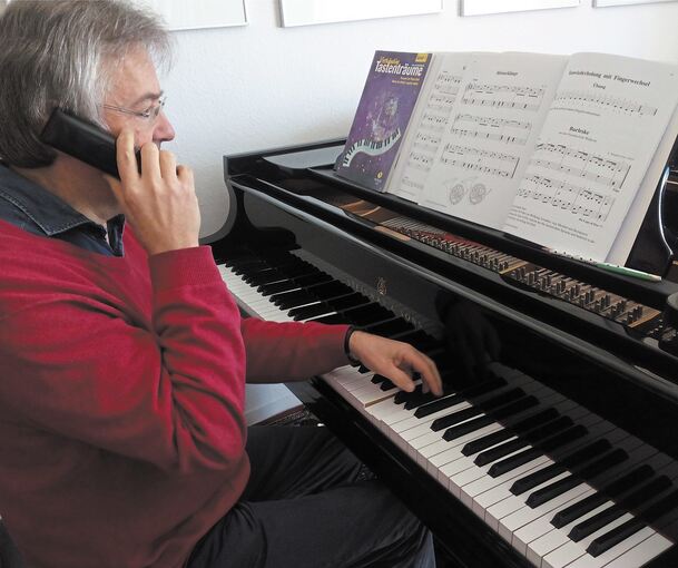 Am heimischen Flügel hat ein Musikschullehrer den Anruf einer Schülerin entgegengenommen; jetzt üben sie gemeinsam den Fingerwechsel. Foto: Andrea Nicht-Roth