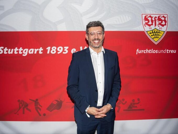 Claus Vogt steht vor einer Wand mit VfB Stuttgart Logo