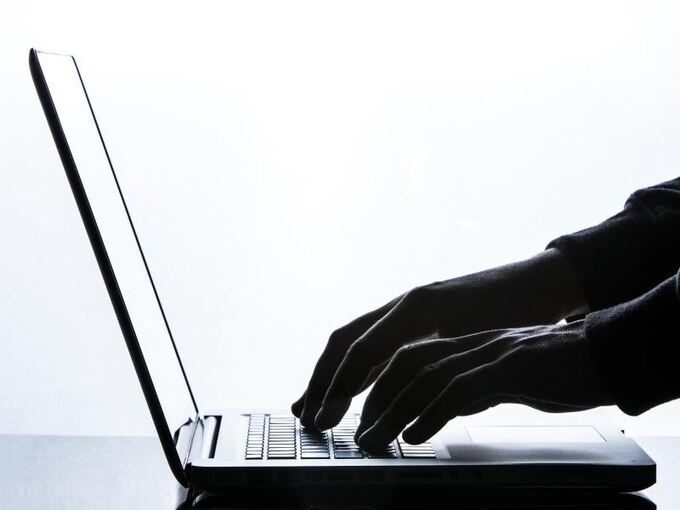 Eine Person tippt auf der Tastatur eines Laptops