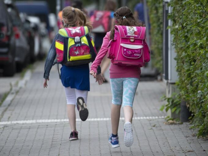 Zwei Schülerinnen rennen die letzten Meter zum Schulhof