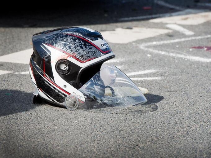Ein beschädigter Motorradhelm liegt nach dem Unfall auf dem Boden