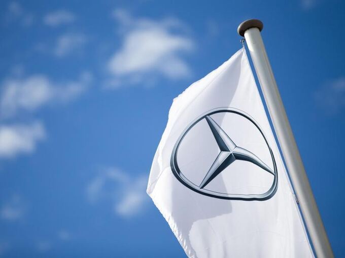 Eine Fahne mit dem Logo von Mercedes-Benz hängt vor blauem Himmel