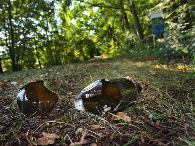Eine zerbrochene Bierflasche liegt neben einem Wanderweg