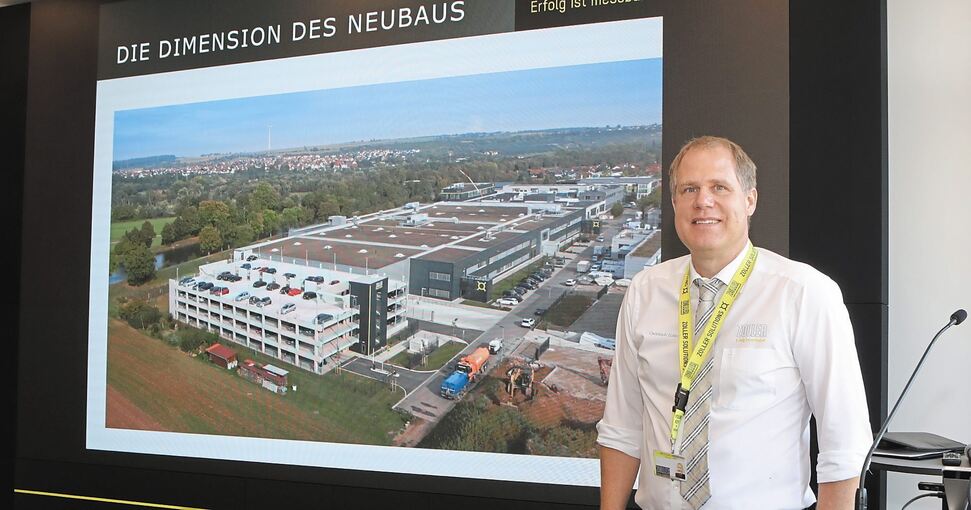 Christoph Zoller, einer von drei Geschäftsführern, vor einem Foto, auf dem der Firmenkomplex in Pleidelsheim zu sehen ist. Foto: Ramona Theiss
