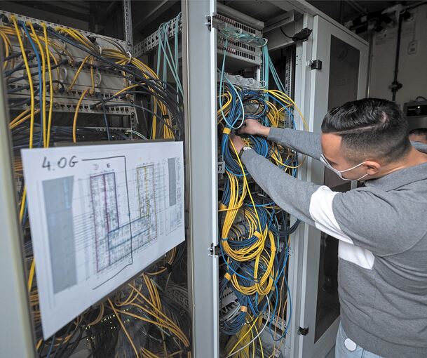 Ein Auszubildender zum Fachinformatiker Systemintegration steckt an einem Server ein Netzwerkkabel ein. Foto: Sebastian Gollnow/dpa