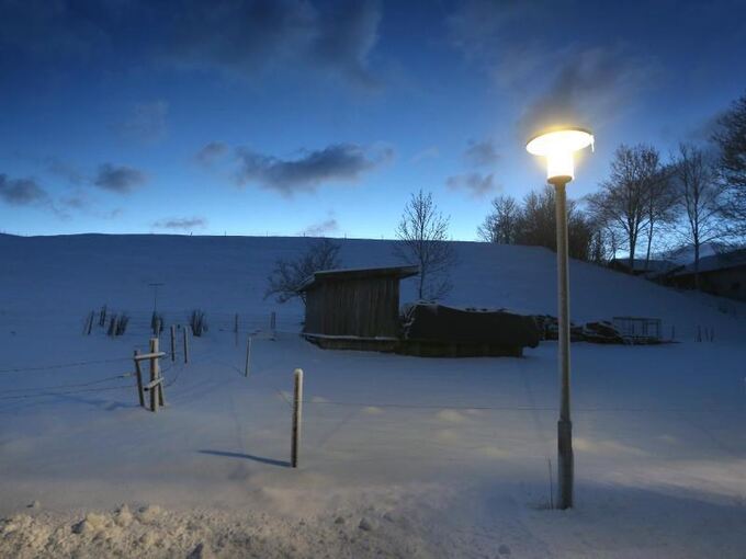 Eine Straßenlampe steht in winterlicher Landschaft