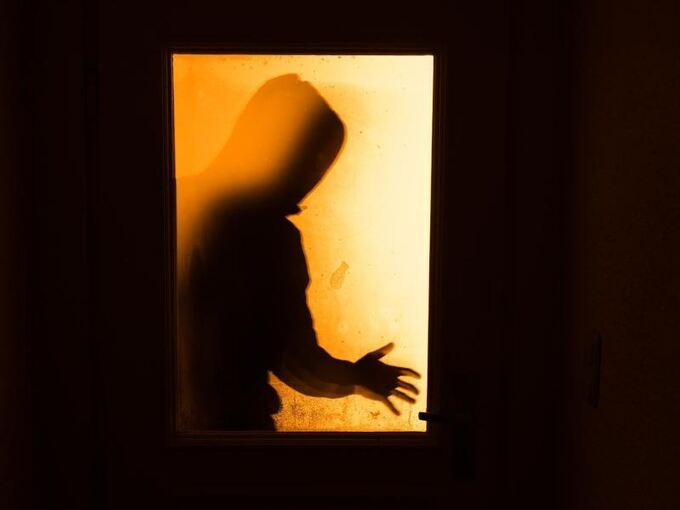 Der Schatten eines Mannes ist hinter einer Glastür zu sehen