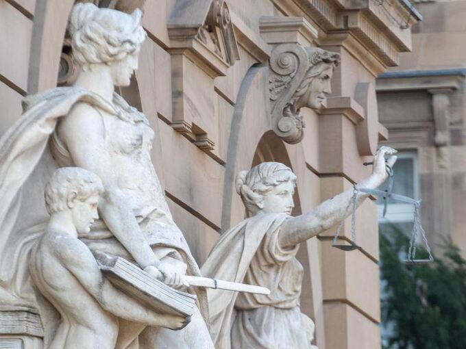 Vor einem Gerichtsgebäude steht u.a. eine Statue der Justitia