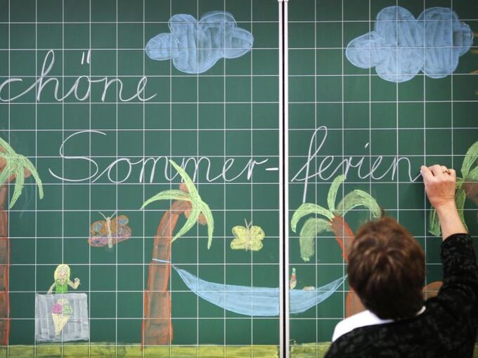 Eine Lehrerin schreibt «Schöne Sommerferien» an eine Tafel