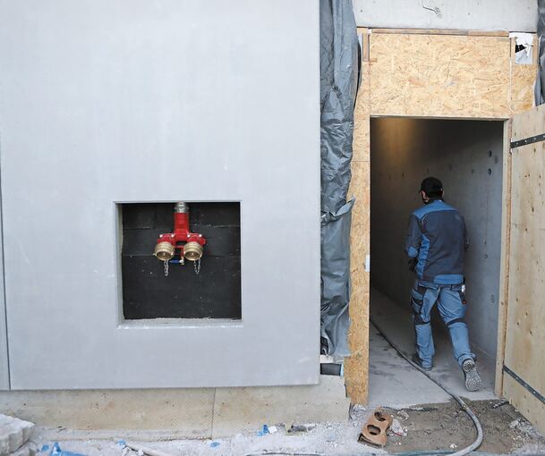 Rote Fensterrahmen und unzählige Klinkersteine zieren bereits einige Fassadenbereiche des neuen Schulgebäudes. Anschlüsse für Feuerwehrschläuche sind bereits eingebaut, während noch zahlreiche Kabel verlegt werden müssen. Der Erste Beigeordnete Stefa