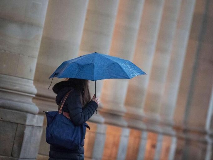 Eine Passantin geht bei Regen durch die Stadt