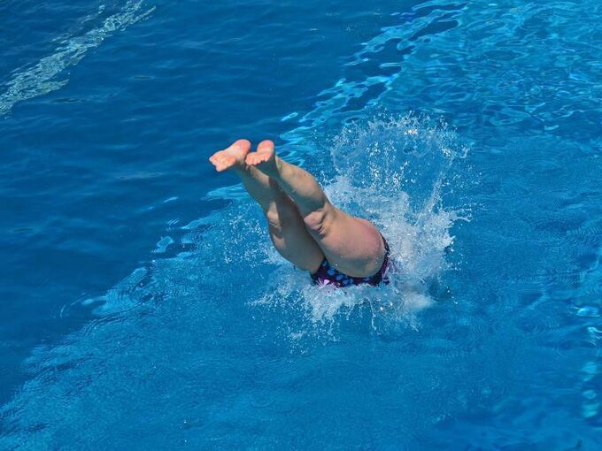 Eine Frau springt in einem Freibad ins Wasser