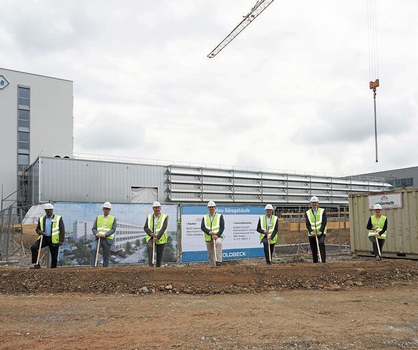 Verspäteter Spatenstich vor der Baugrube des künftigen Forschungs- und Entwicklungszentrums. Im Hintergrund die Produktions- und Logistikhalle sowie der Büroturm. Fotos: Andreas Becker