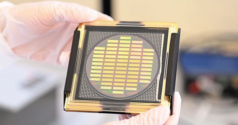 In einem Labor der Firma Q.uant hält ein Mitarbeiter einen Wafer mit neuentwickelten Chips zum Einsatz in Quantencomputern. Foto: Bernd Weißbrod/dpa