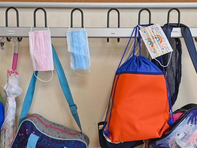 Masken und Taschen hängen in einer Grundschule an Kleiderhaken