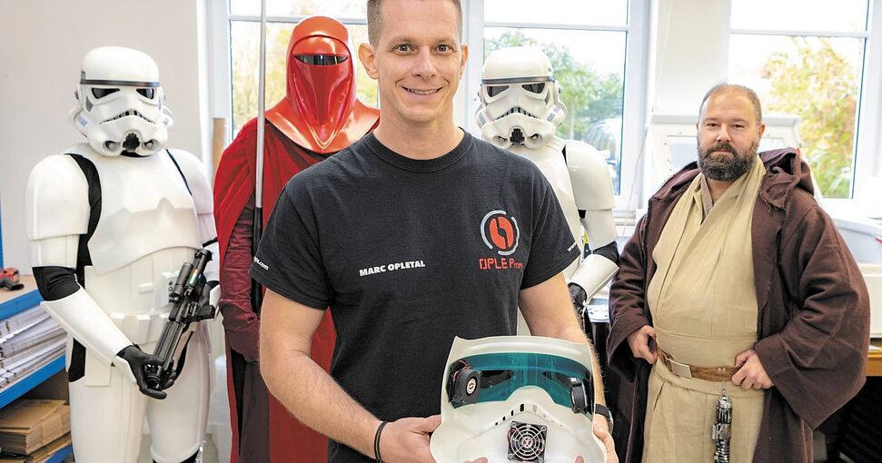 Marc Opletal, umringt von Kostümierten, zeigt in der Cosplay-Werkstatt in Beilstein einen Helm mit Mini-Ventilator. Foto: Andreas Essig