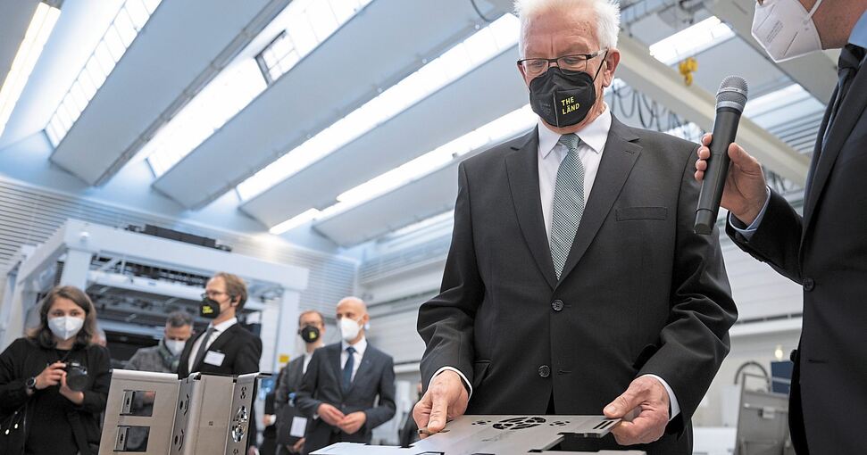 Ministerpräsident Kretschmann schaut sich in der Smart Factory ein Werkstück genau an.