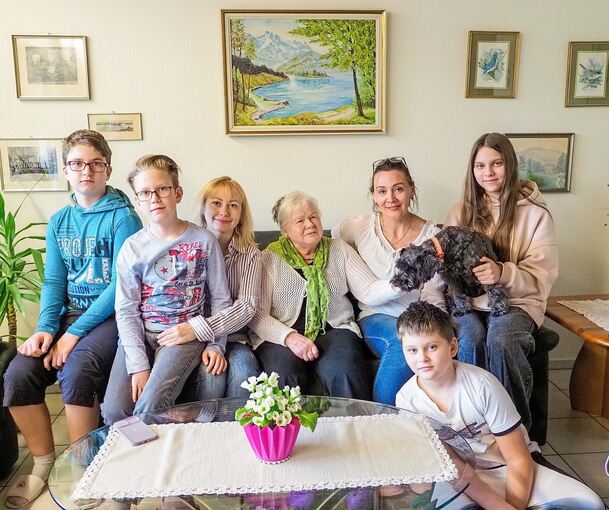 Gerda Mosny mit ihren neuen Mitbewohnern auf der Wohnzimmercouch (von links): Illia, Rodion und Ira Cherednyk. Rechts neben Mosny sitzt Tanja Zadorozna mit ihrer Tochter Katja und ihrem Sohn Artem. Katja trägt Hund Rocky auf dem Schoß.Foto: Holm Wols