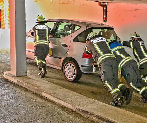 Mit Muskelkraft schiebt die Feuerwehr das Auto aus der Tiefgarage. Fotos: KS-Images.de / Andreas Rometsch