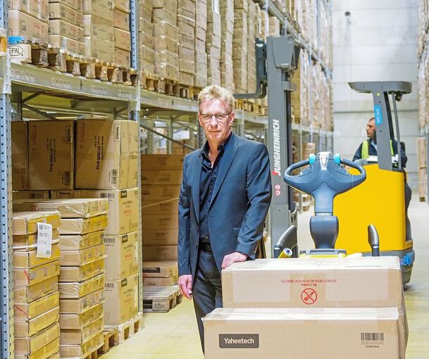 Stapelweise Waren in Kartonagen: Tobias Gutekunst, Geschäftsführer der Yahee GmbH, in einer Versandhalle. Auf dem Gefährt hinten sitzt Lagermitarbeiter Ivaylo Dimitrov. Foto: Holm Wolschendorf