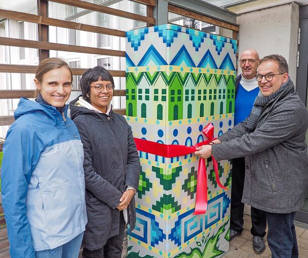 Die Initiatorinnen und Initiatoren enthüllen den Fairteiler am Zugang zum Gemeindesaal der katholischen Kirche in der Marbacher Ziegelstraße: Eva Ludwig, Rebeca Jerónimo, Pfarrer Stefan Spitznagel und Gero Nenninger (von links). Foto: Holm Wolschendo