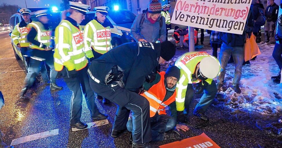Die Polizisten versuchen, den Aktivisten von der Straße zu ziehen. Doch seine Hand klebt fest. Foto: Holm Wolschendorf