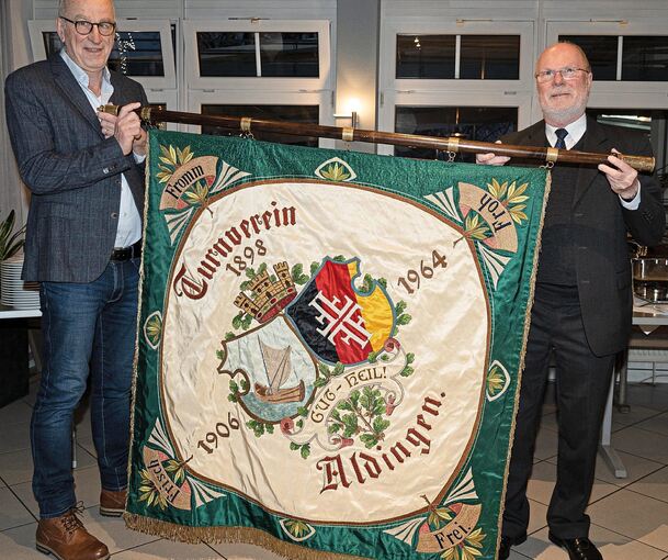 Die TVA-Vorsitzenden Dr. Thomas Schulz und Gert Heidemann (links) präsentieren den Gästen des Jubiläumsempfangs die Traditionsfahne des Vereins.