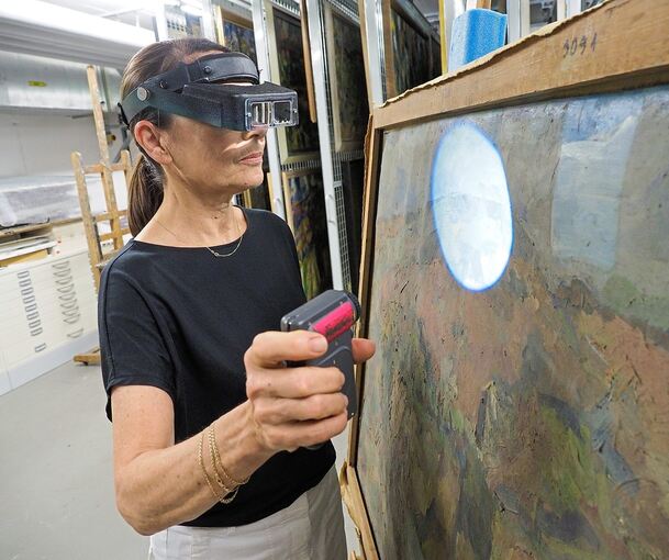 Sabine Hofmeister untersucht die vergilbte Oberfläche des Gemäldes. Foto: Holm Wolschendorf