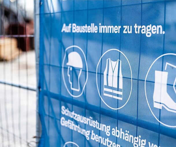 Wichtige Schutzausrüstung: Sicherheitshinweise am Zaun einer Baustelle. Foto: IG Bau/p