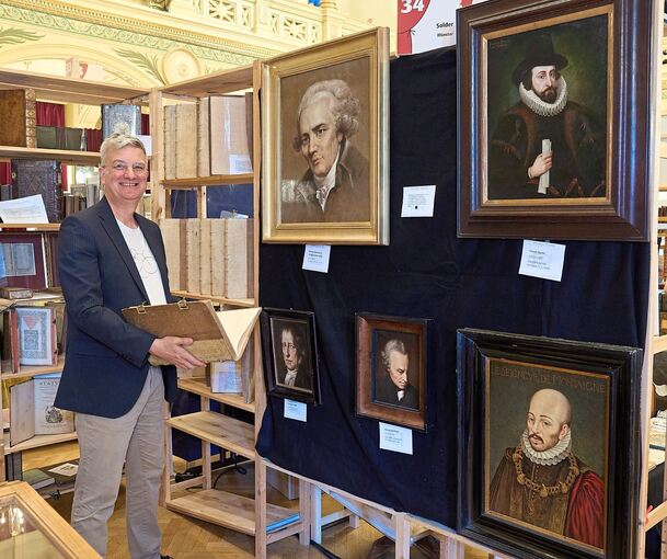 Der Münsteraner Antiquar Michael Solder mit seinen Ölgemälden bekannter Köpfe. Foto: Andreas Becker